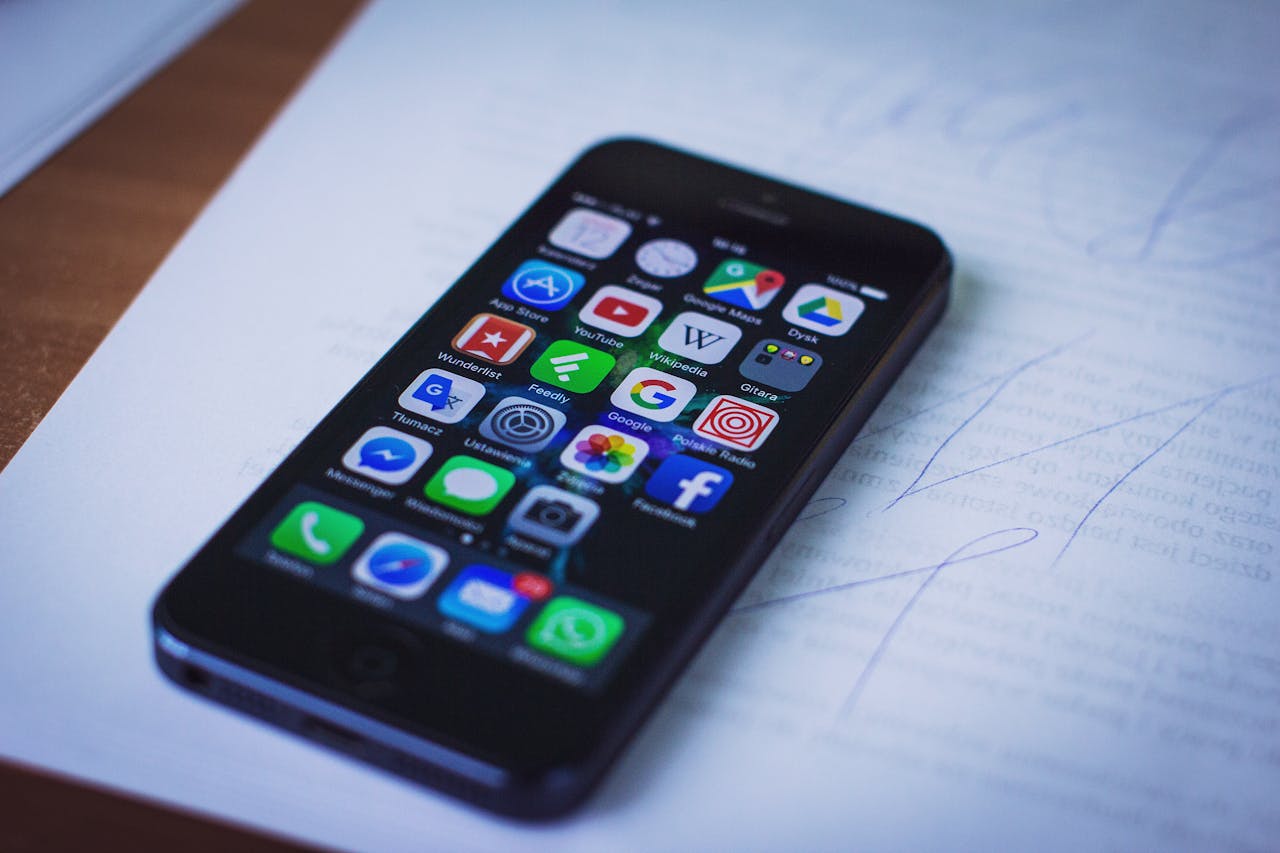 Modern smartphone displaying various apps resting on documents indoors.