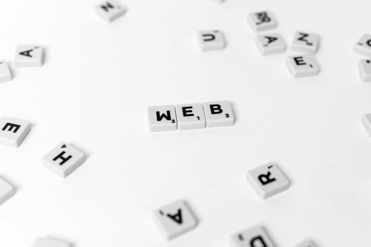 Scattered Scrabble tiles emphasize the word 'WEB' on a minimalist white background.